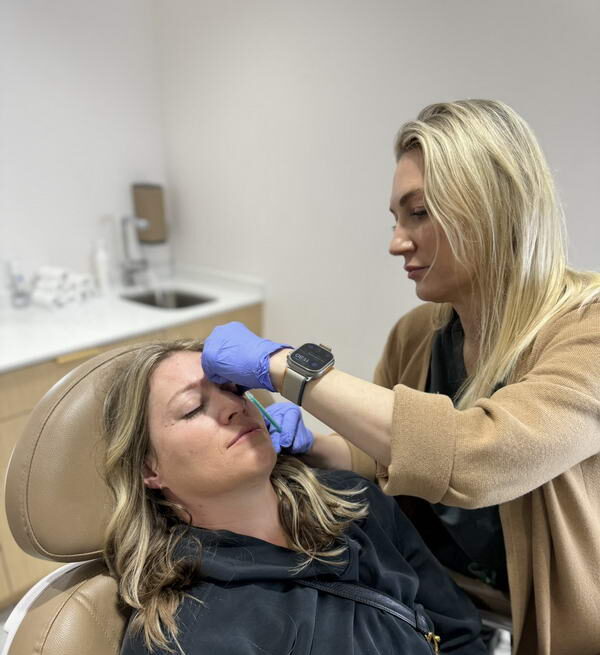 A Glow Theory injector treating a patient’s brow area with Botox