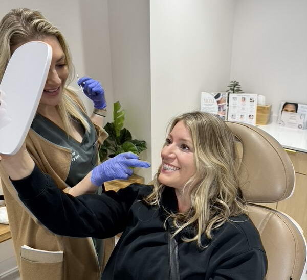 A Glow Theory patient smiling at her Botox result in a hand mirror